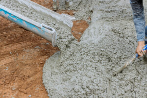 Concrete is poured into parking driveways for cars by a worker in construction site